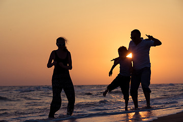 Image showing Father mother and  son  playing on the beach at the sunset time.