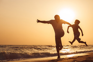 Image showing Father and son  playing on the beach at the sunset time.