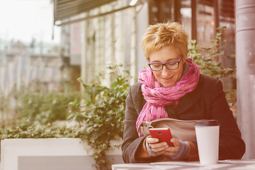 Image showing Smiling woman with phone in cafe