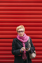 Image showing Woman with phone at red fence