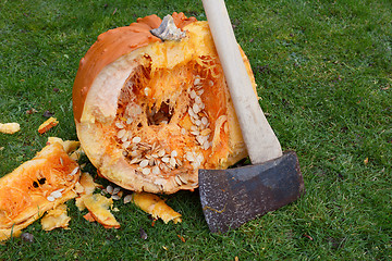 Image showing Long-handled axe against a warty orange pumpkin