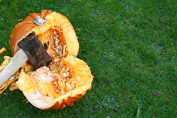 Image showing Axe hacks a large orange pumpkin in half