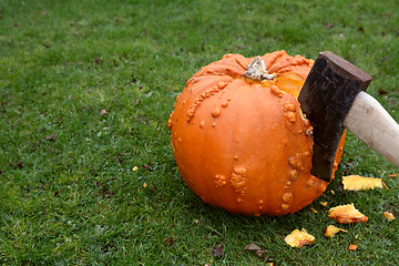 Image showing Axe hacking into a large orange pumpkin