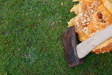 Image showing Sharp axe against a large pumpkin, hacked open