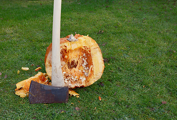 Image showing Axe against large pumpkin, roughly cut in half