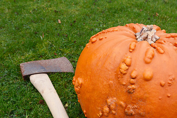 Image showing Sharp axe on grass with orange pumpkin