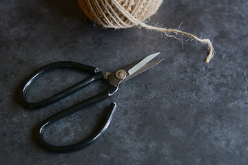 Image showing Scissors with rough twine on a grey tile background 