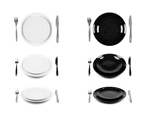 Image showing Two sets of white and black plates with fork and knife