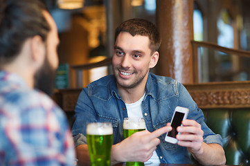 Image showing friends with smartphone drinking green beer at pub