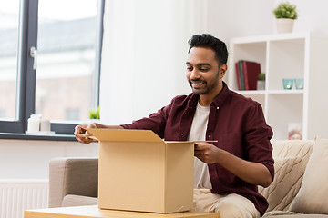 Image showing happy man opening parcel box at home