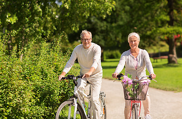 Image showing happy senior couple riding bicycles at summer park