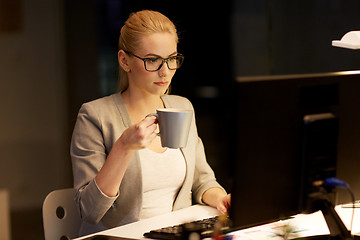 Image showing businesswoman at night office drinking coffee