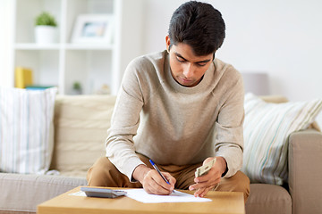 Image showing man with money and calculator filling papers