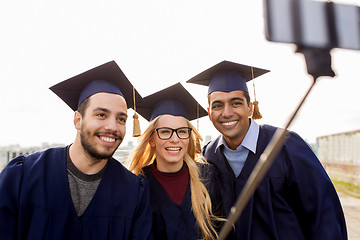 Image showing happy students or graduates taking selfie outdoors