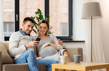 Image showing man and pregnant wife with smartphone at home