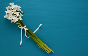 Image showing White narcissi, tied with ribbon on a blue background