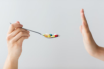 Image showing close up of female hand holding spoon with pills