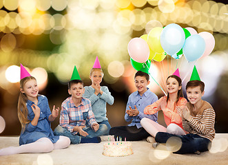 Image showing happy children in party hats with birthday cake