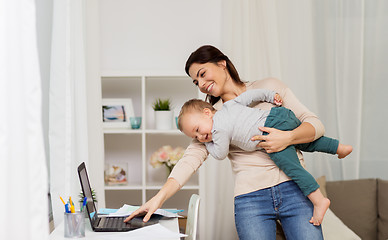 Image showing happy mother with baby and laptop working at home