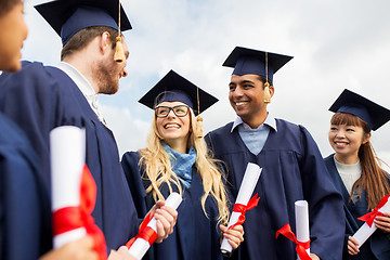 Image showing happy students in mortar boards with diplomas