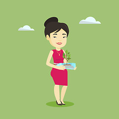 Image showing Woman holding plant growing in plastic bottle.