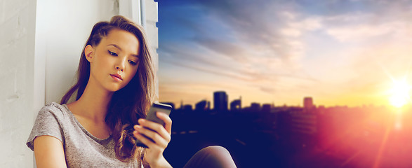 Image showing sad pretty teenage girl with smartphone texting