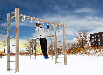 Image showing young man exercising on horizontal bar in winter