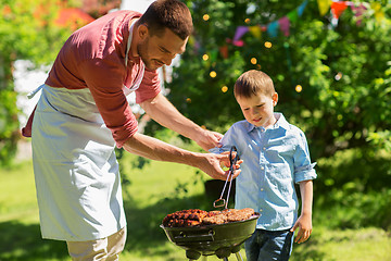 Image showing father and son cooking meat on barbecue grill