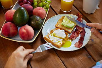 Image showing man eating toast with pouched egg and bacon