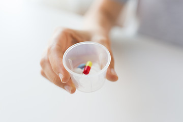 Image showing close up of female hand with pills in medicine cup