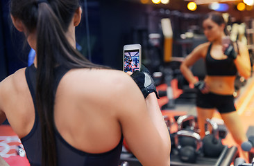 Image showing woman with smartphone taking mirror selfie in gym