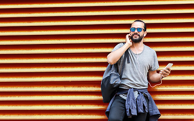 Image showing man with earphones and smartphone over wall