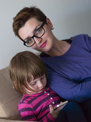 Image showing mother and her cute little daughter are using a mobile phone