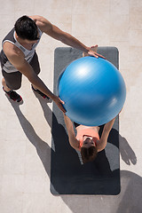 Image showing woman and personal trainer doing exercise with pilates ball