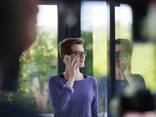 Image showing young women using mobile phone by the window