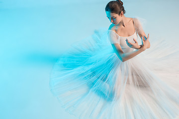 Image showing Young and incredibly beautiful ballerina is dancing in a blue studio