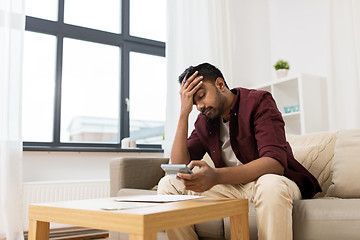 Image showing upset man with papers and calculator at home