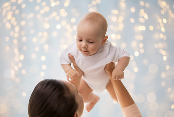 Image showing happy mother playing with little baby boy over lights