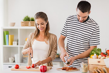 Image showing happy couple cooking food at home kitchen