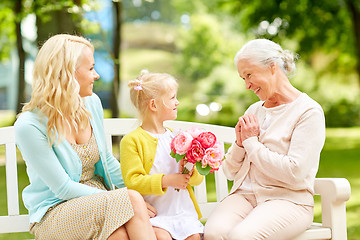 Image showing happy family giving flowers to grandmother at park