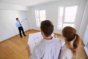 Image showing realtor showing new home to couple with blueprint