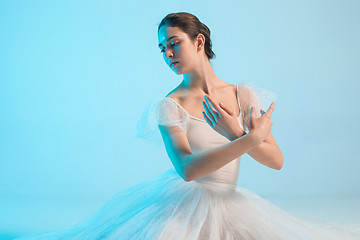 Image showing Young and incredibly beautiful ballerina is dancing in a blue studio