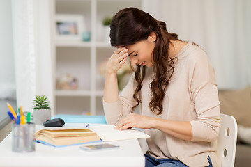 Image showing tired female student with book learning at home