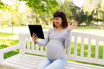 Image showing happy pregnant asian woman with tablet pc at park