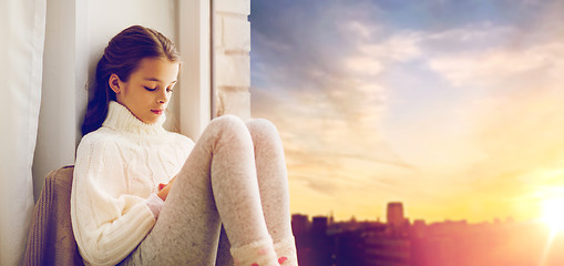 Image showing sad girl sitting on sill at home window