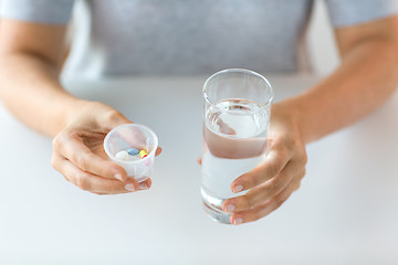 Image showing close up of hands with pills and glass of water