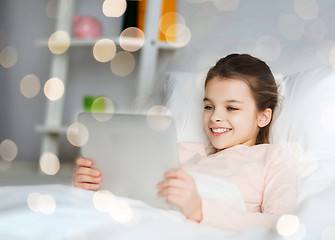 Image showing happy girl lying in bed with tablet pc at home