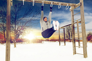 Image showing young man exercising on horizontal bar in winter