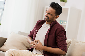 Image showing unhappy man suffering from stomach ache at home