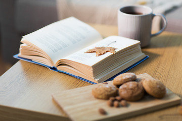 Image showing book with autumn leaf, cookies and tea on table